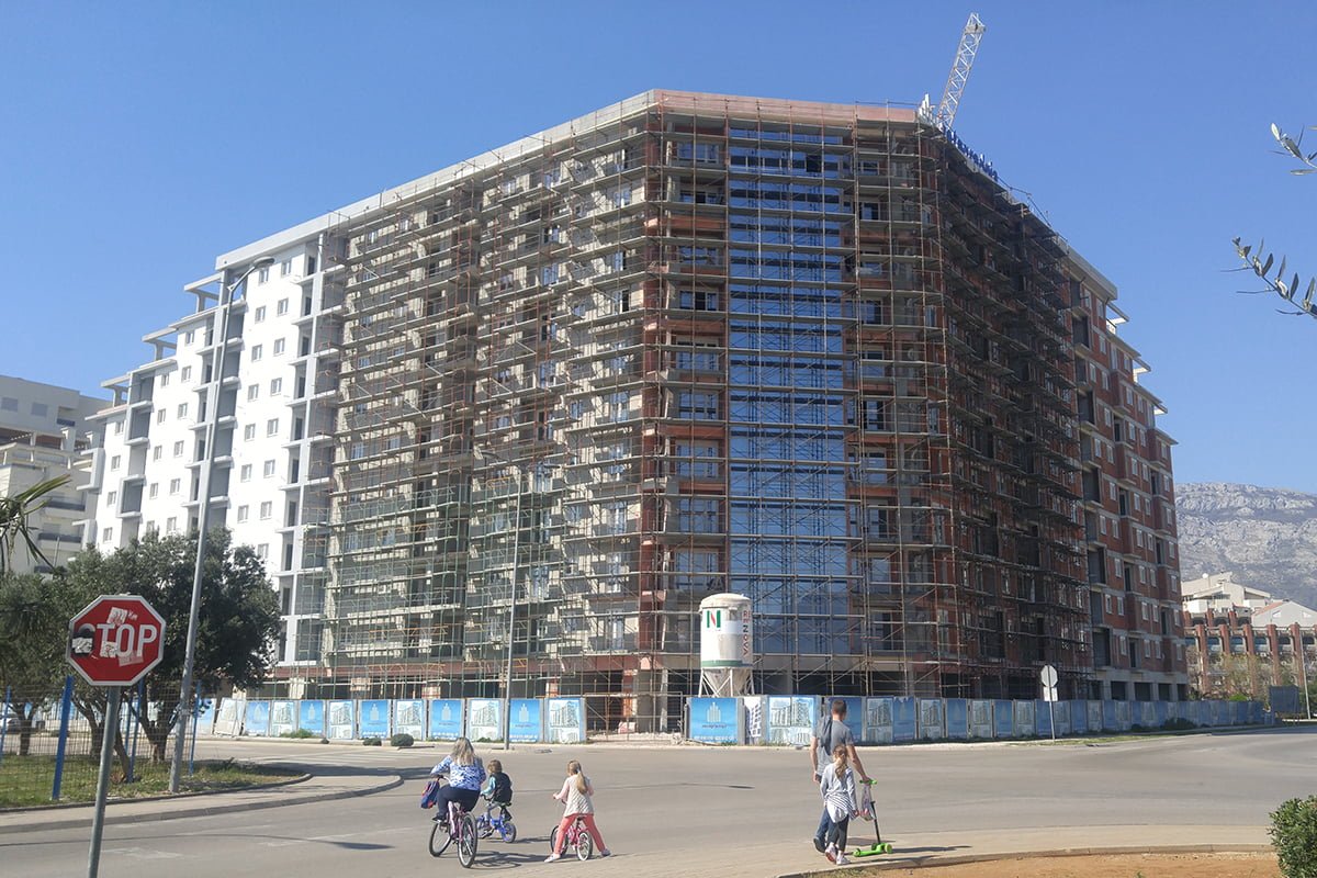 Residential complex under construction in the city of Bar, Montenegro: building facade with scaffolding and panoramic glazing.