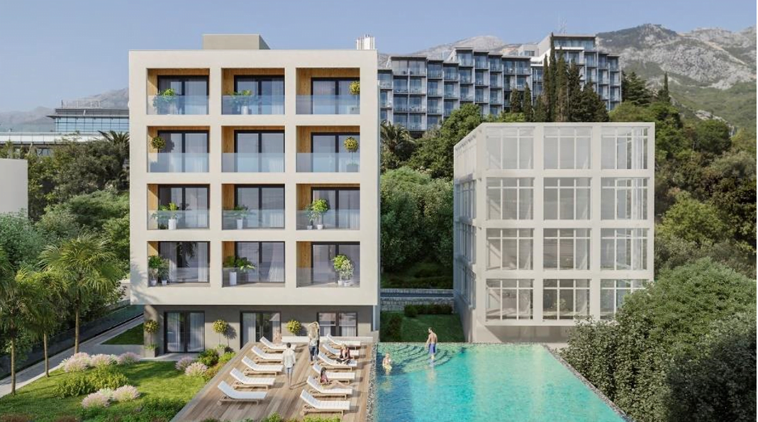 Modern residential complex with a swimming pool and terrace in Bečići, Montenegro: view of the building facade and green area.
