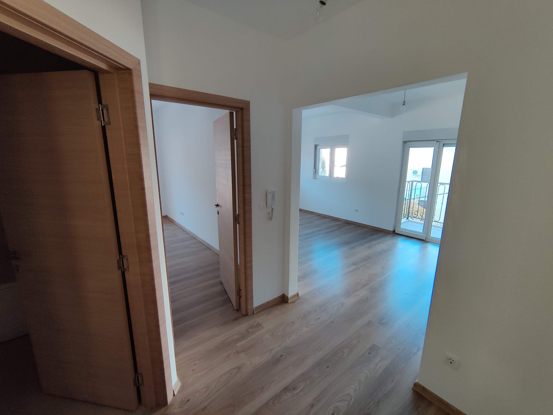 Bright living room with laminate flooring and access to the balcony in an apartment in Bečići, Montenegro. View of the interior doors.