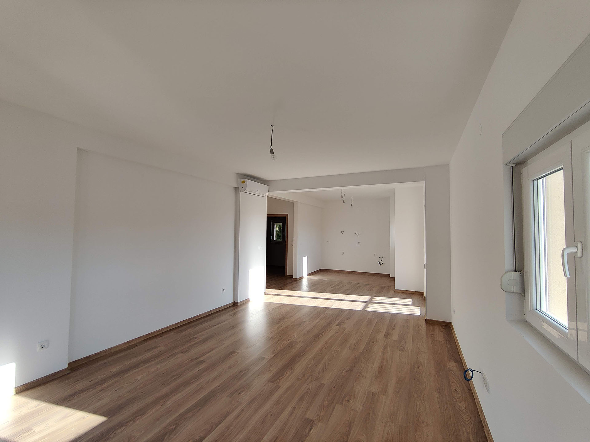 Bright living room with laminate flooring in a new apartment in Bečići, Montenegro: finished interior, air conditioning, and plastic windows.