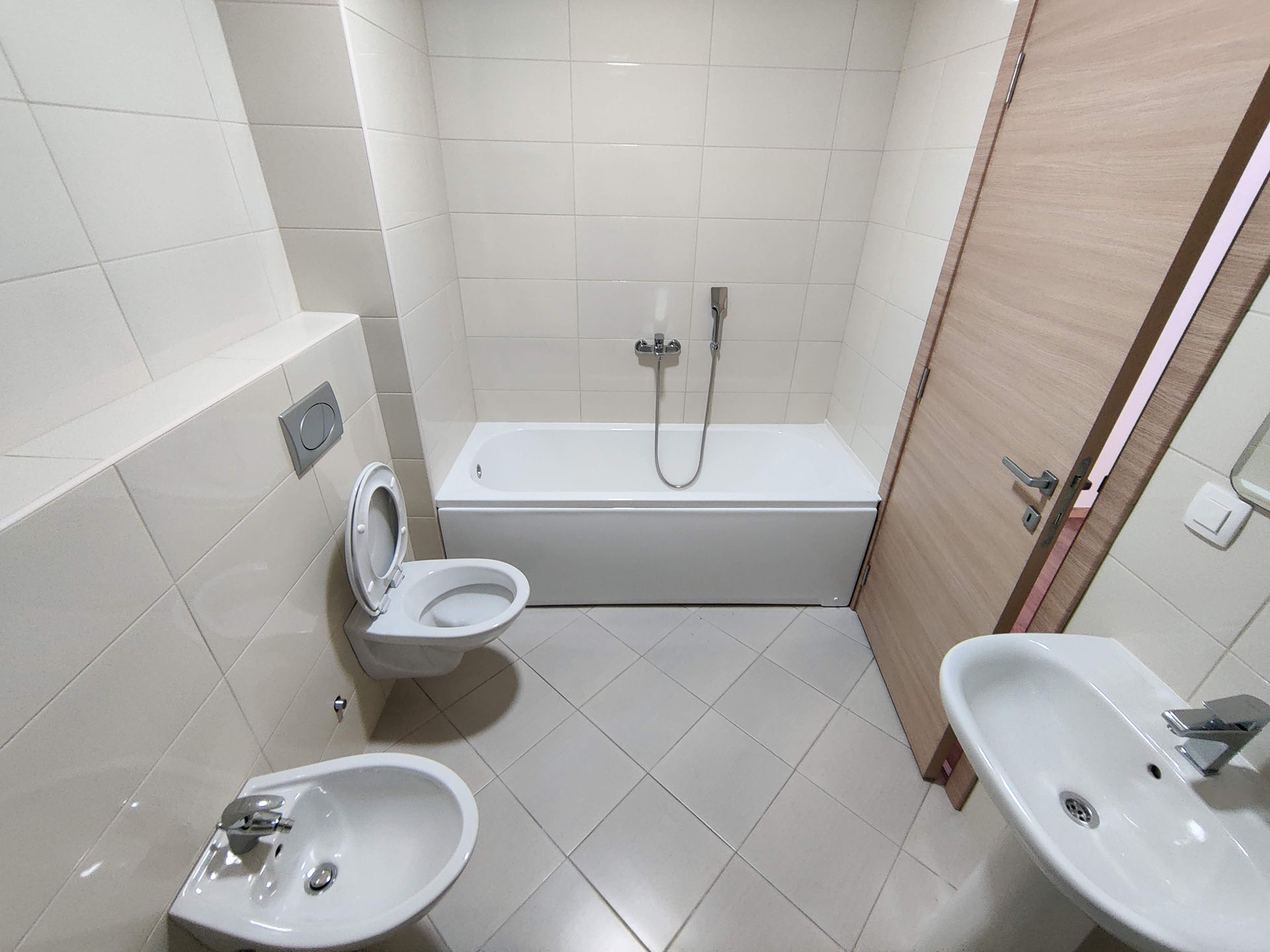 Bright bathroom in an apartment in Bečići, Montenegro: bathtub, wall-hung toilet, bidet, and modern tile finish.