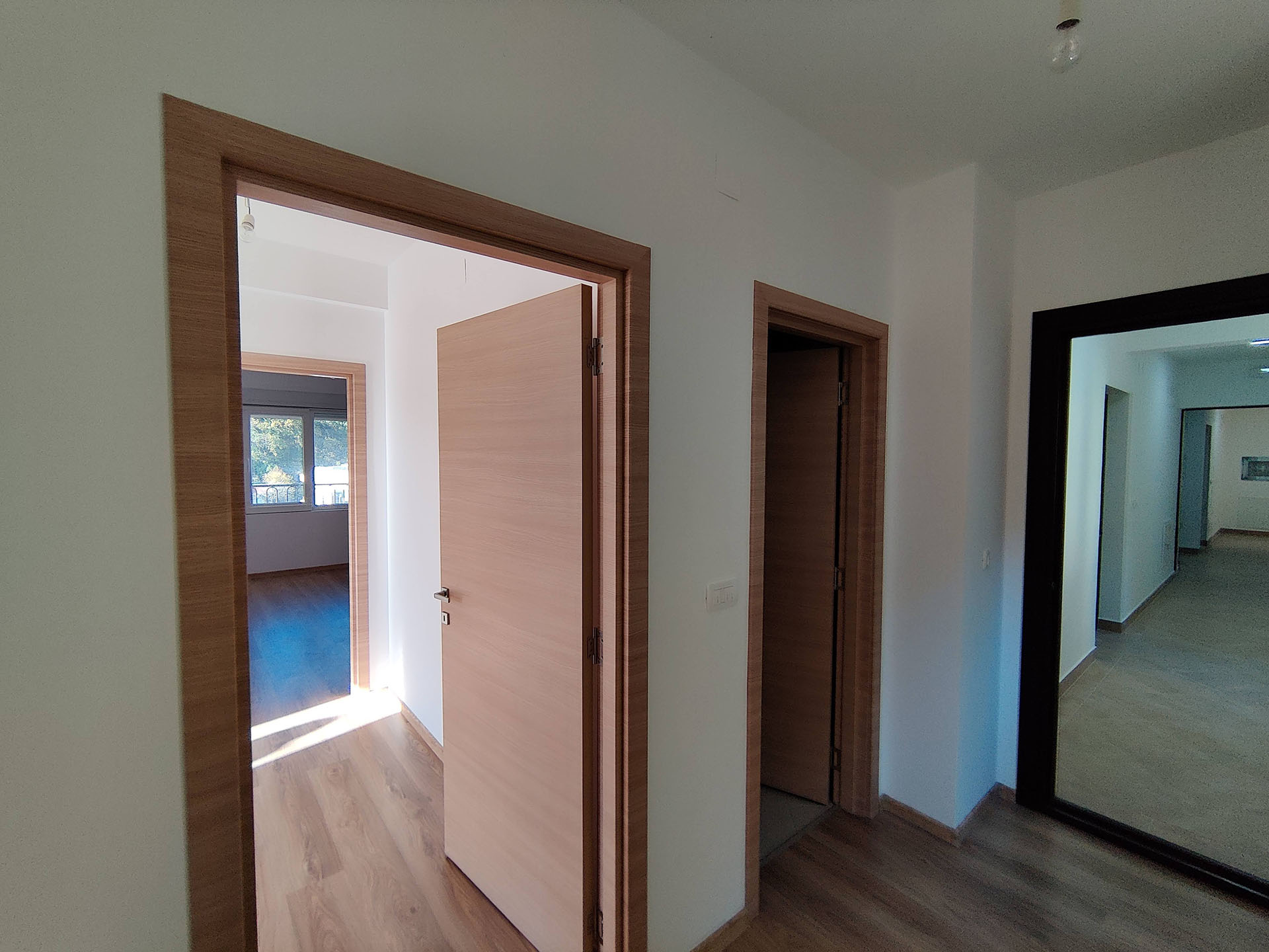 Bright hallway with wood-finish interior doors in an apartment, Bečići, Montenegro. View of adjoining rooms.