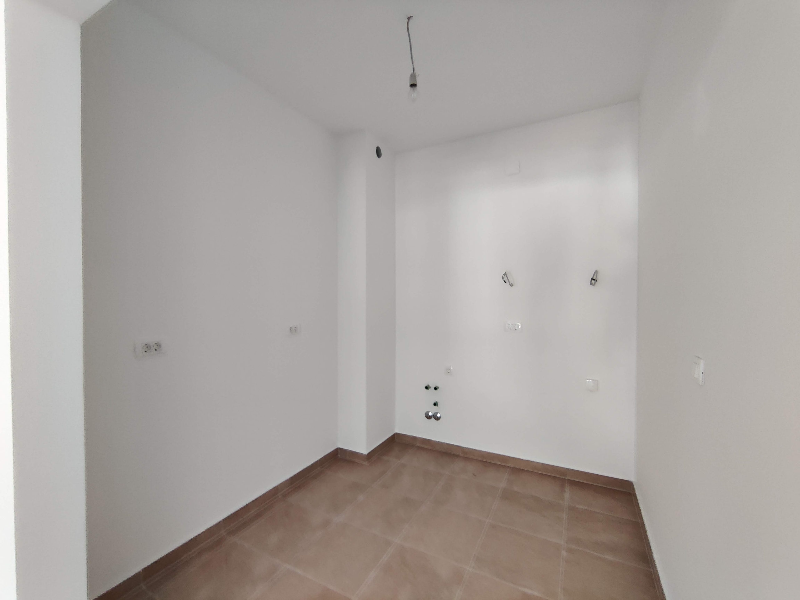 Empty kitchen with white finishes and utility connections in a new apartment, Bečići, Montenegro.