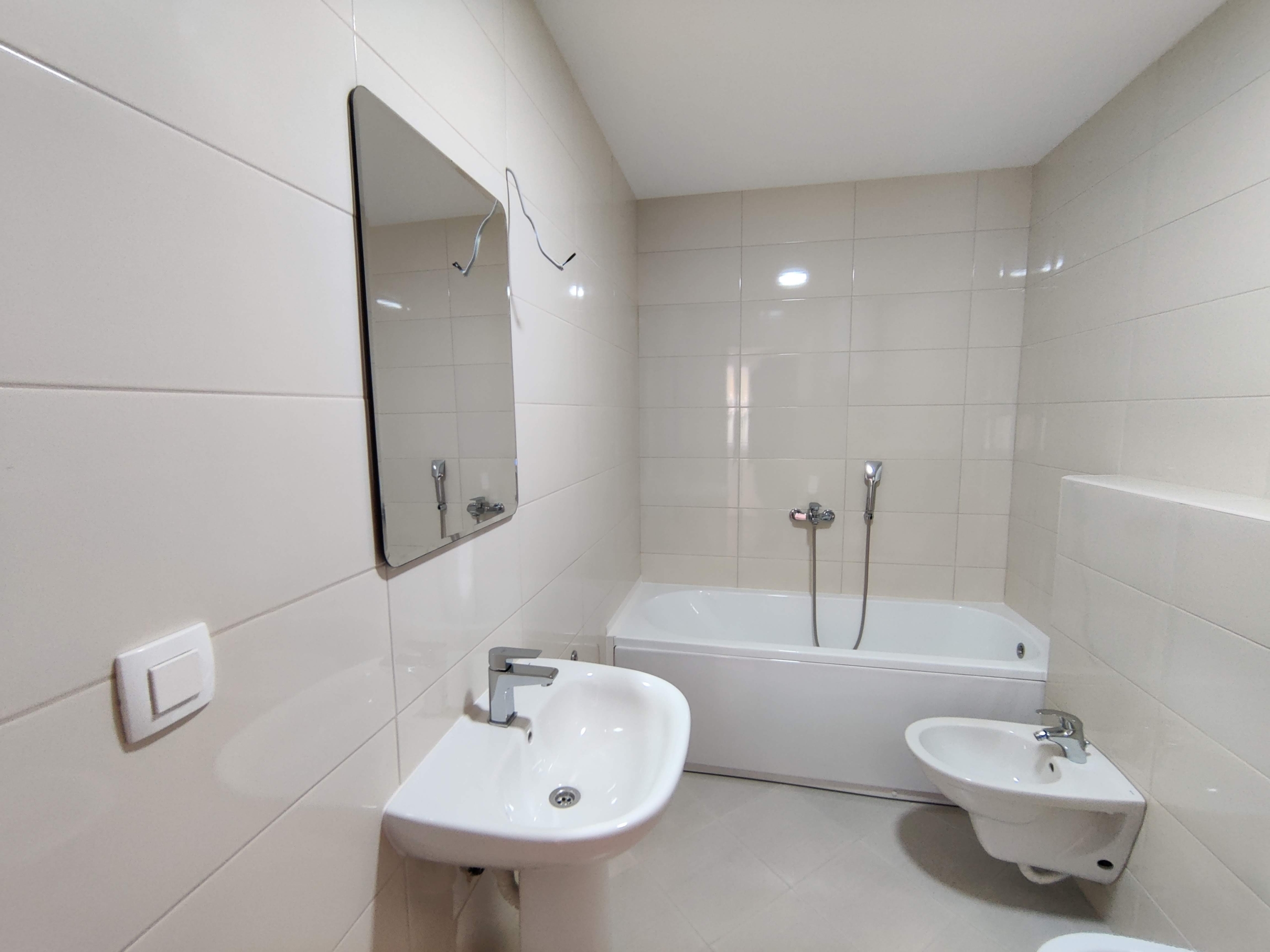 Bright bathroom with a bathtub and bidet in an apartment, Bečići, Montenegro: modern tile finishes and plumbing fixtures.