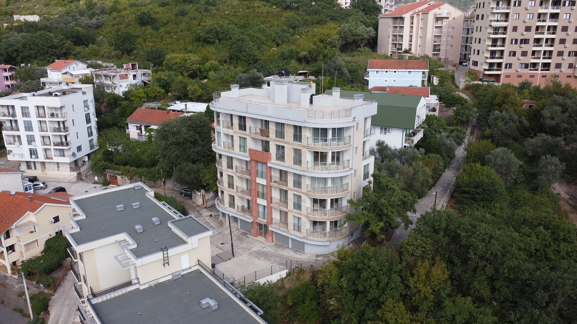 Modern residential building with balconies in Bečići, Montenegro: aerial view of the building and surrounding greenery.