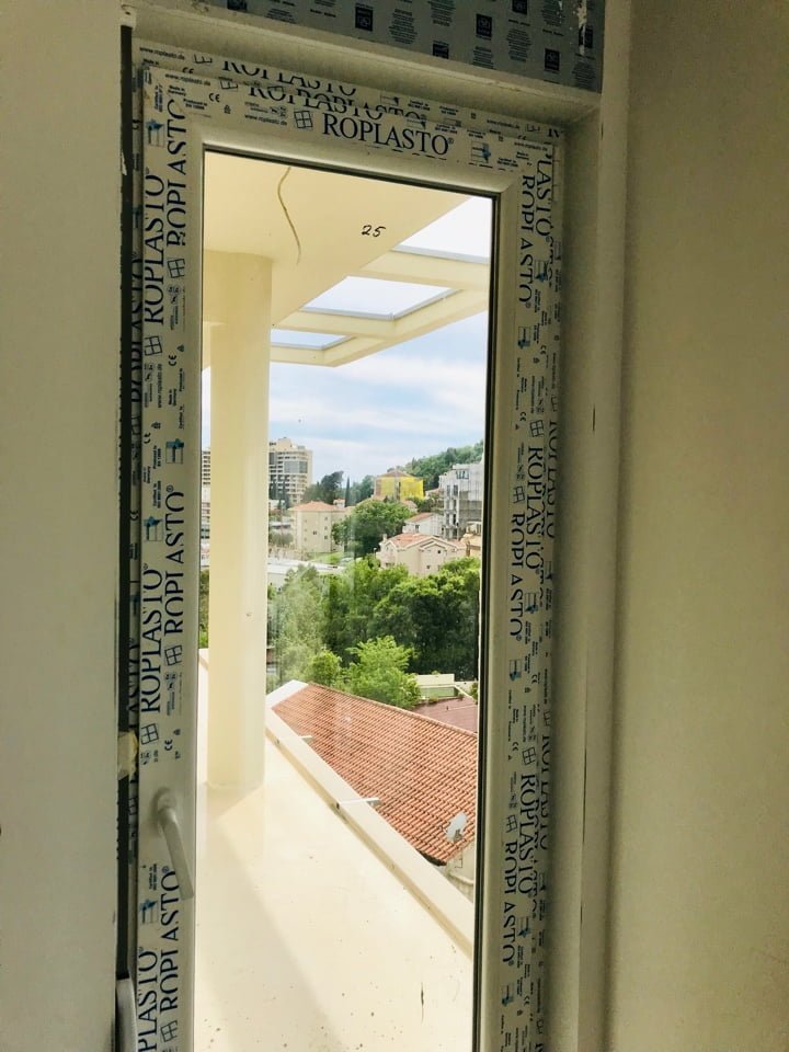View from the balcony of the city of Bečići in Montenegro through a new Roplasto double-glazed plastic window in a building under construction.