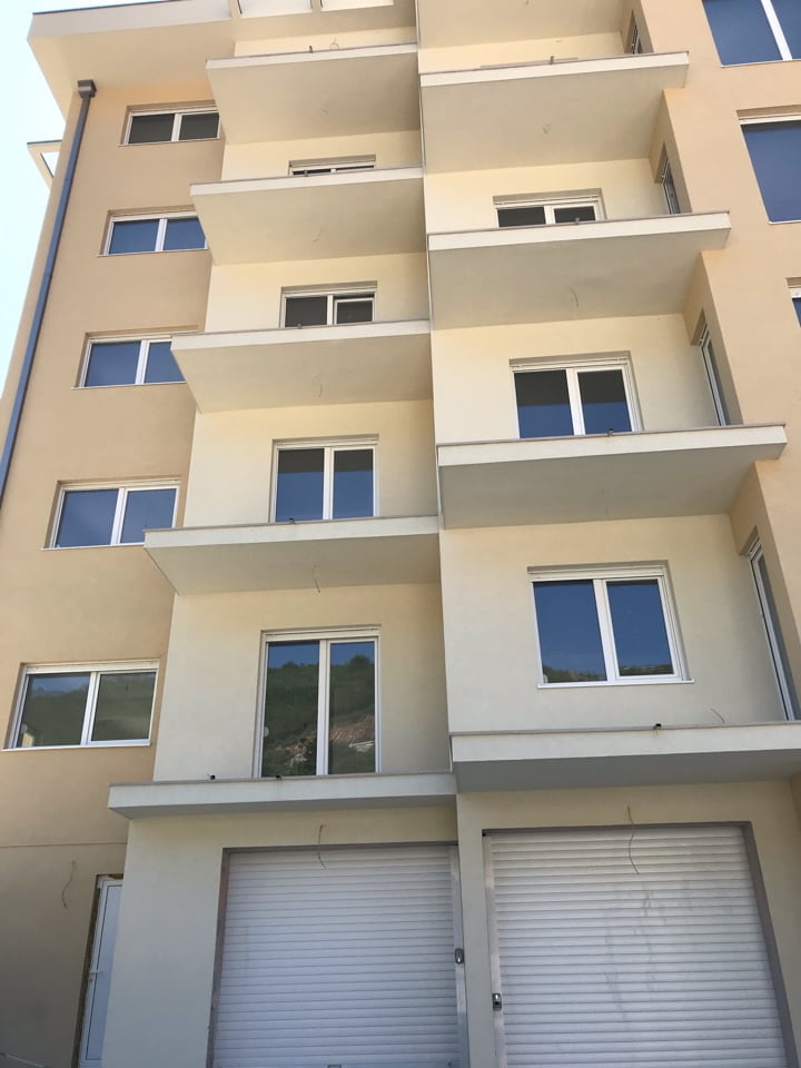 Facade of a modern apartment building with balconies in Bečići, Montenegro: view of the building with garage roller shutters.