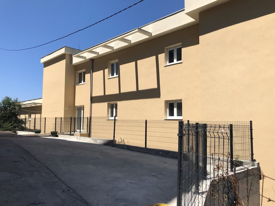 Facade of a modern two-story house in Bečići, Montenegro, with a fenced area and asphalt parking.