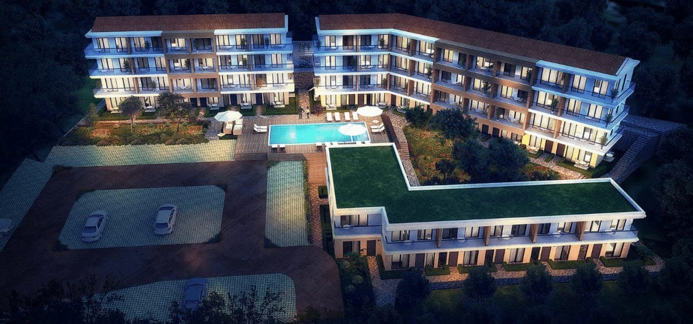 Residential complex in Kavac, Montenegro: top view of modern apartments with a swimming pool and parking at night.