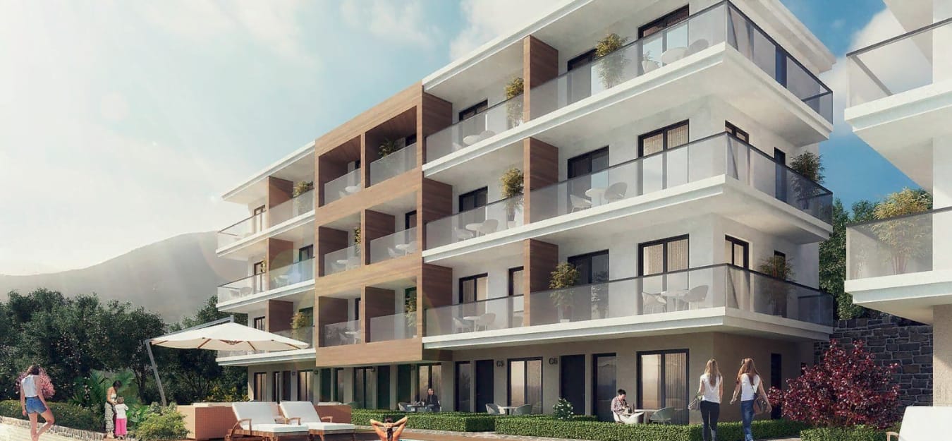 Exterior view of a modern multi-story residential building with balconies, ground terrace, and people against mountains.