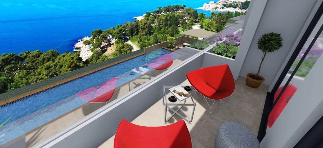 Balcony with red chairs and infinity pool overlooking the sea and greenery.