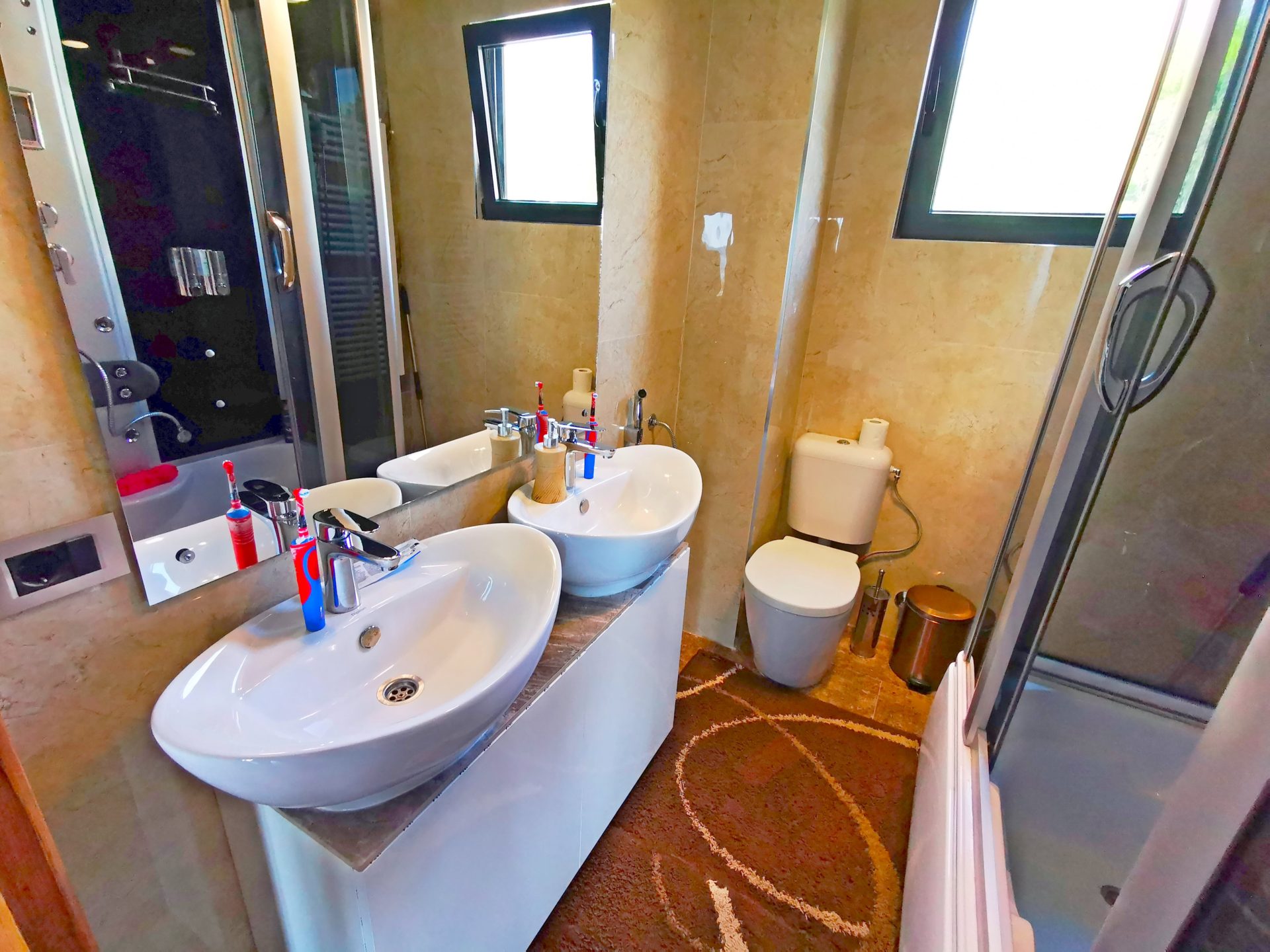 Modern bathroom with two sinks and a shower cabin in a villa in Bar, Montenegro.