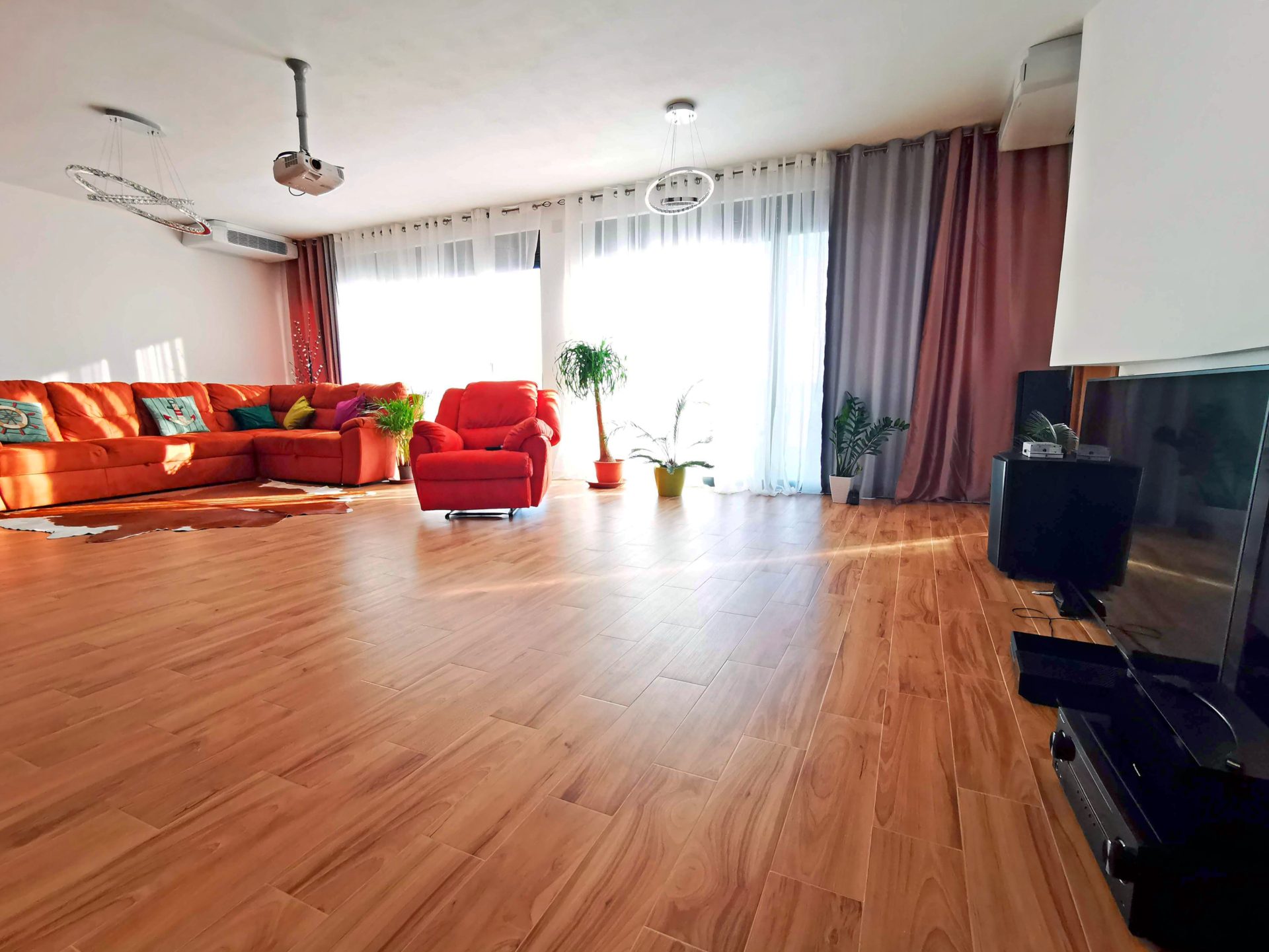 Spacious living room with a red sofa and projector in a villa in Bar, Montenegro. Bright interior with panoramic windows.