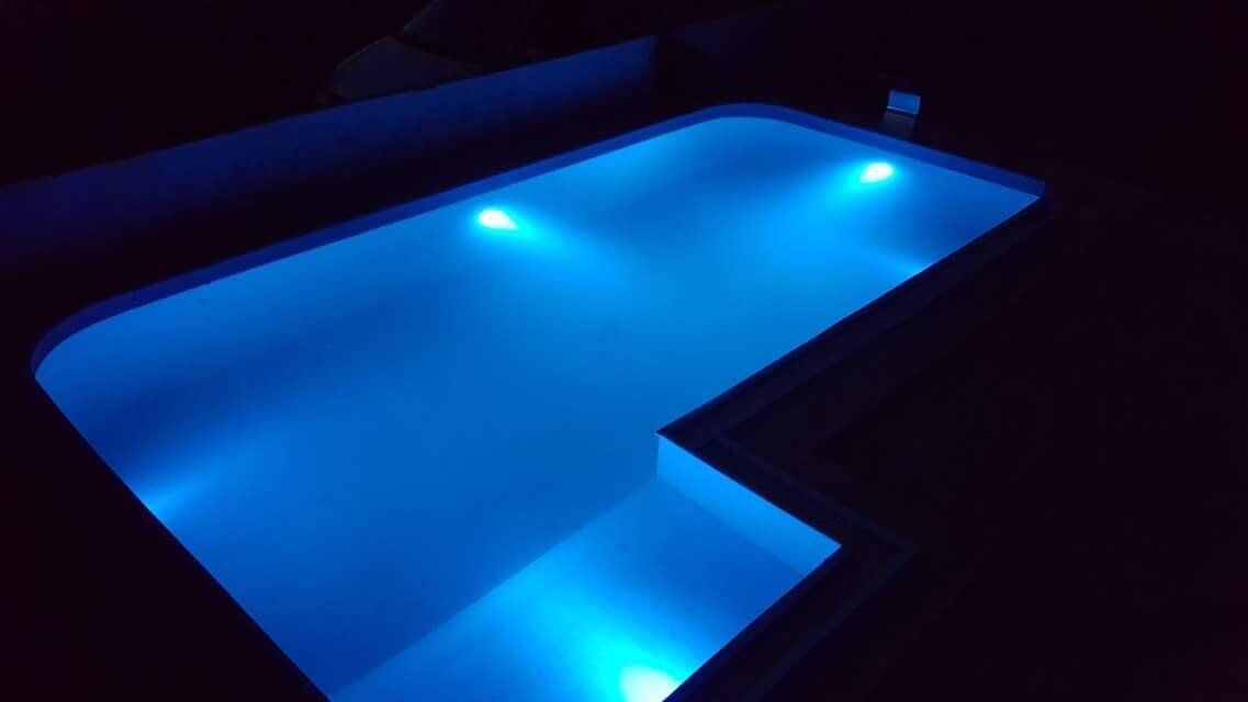 Open-air swimming pool with neon lighting on the villa grounds in the city of Bar, Montenegro, night view.