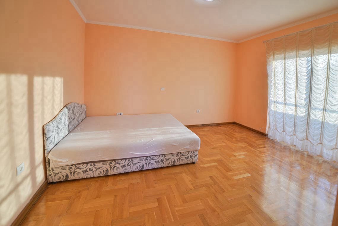 Bright bedroom with a double bed, parquet flooring, and a panoramic window in an apartment, Utjeha, Montenegro.