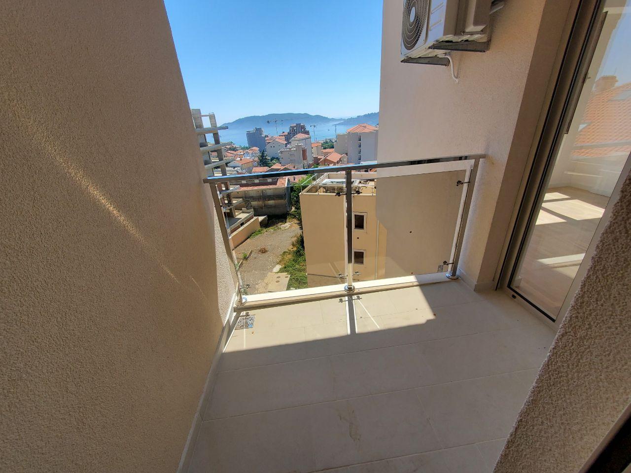 Balcony with panoramic sea and mountain views in a residential building in Bečići, Montenegro, with a modern glass railing.