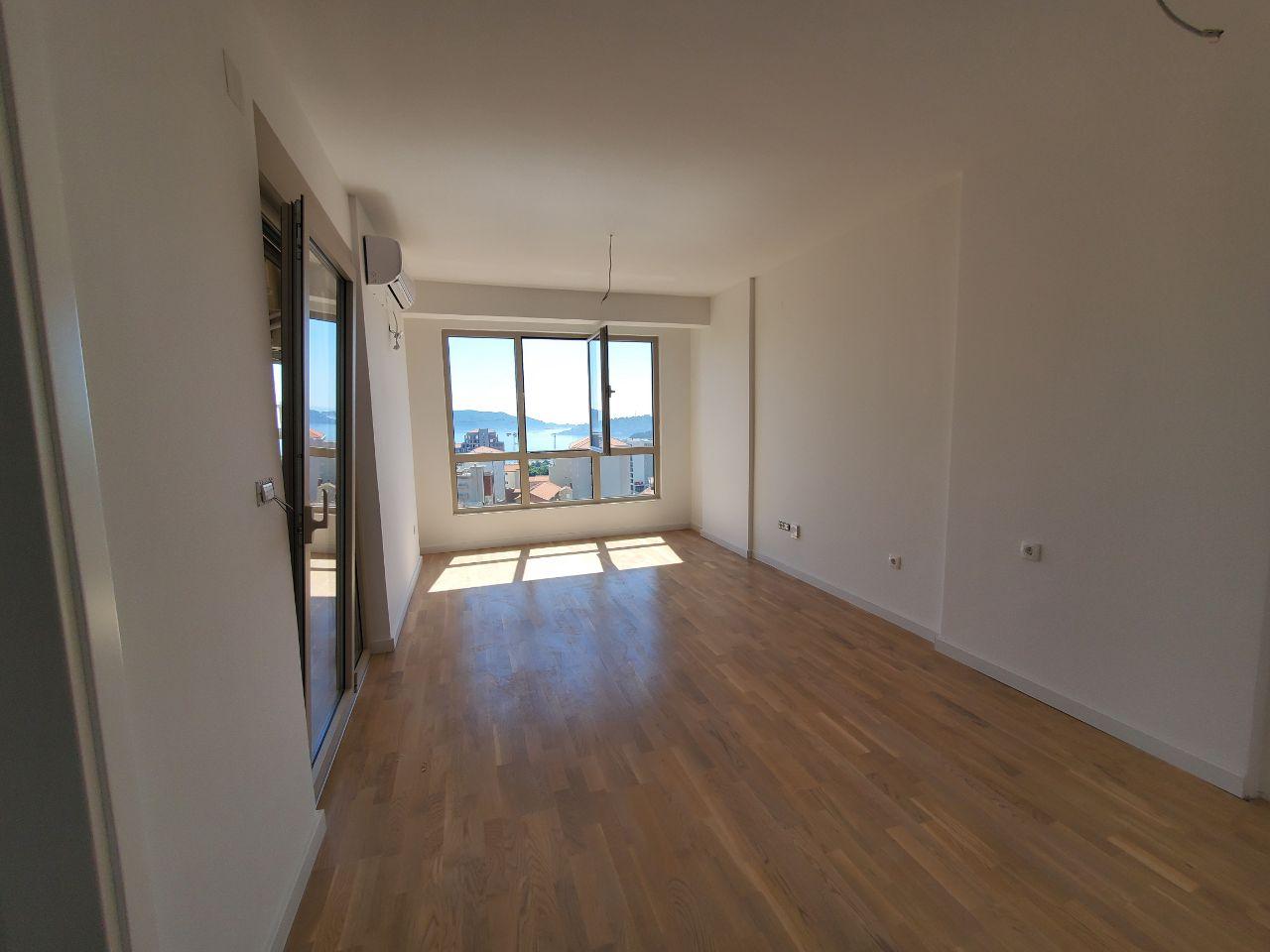 Bright living room with parquet flooring and panoramic sea view in a residential building in Bečići, Montenegro.