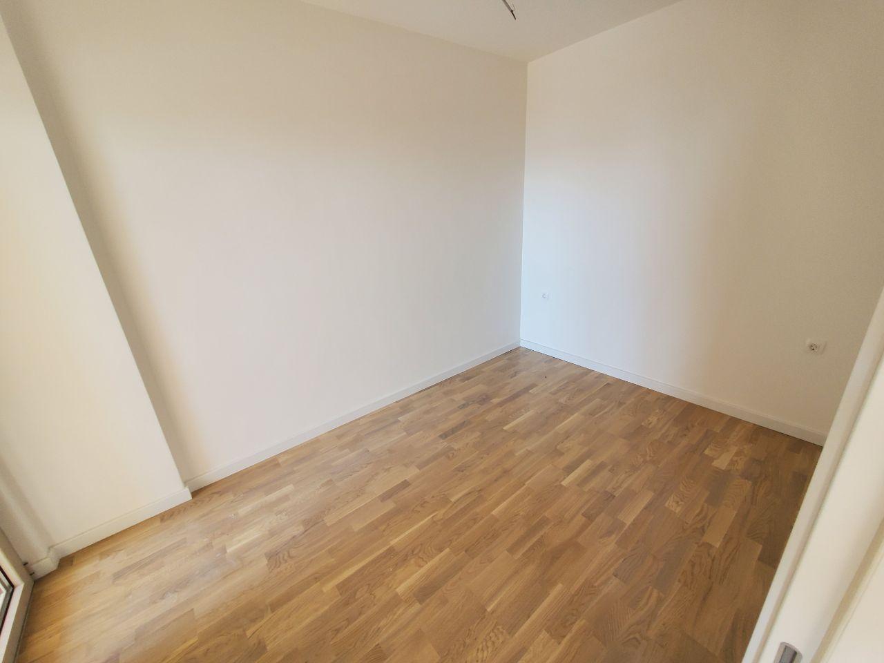 Bright empty bedroom with parquet flooring in a residential building in Bečići, Montenegro, ready to be furnished.
