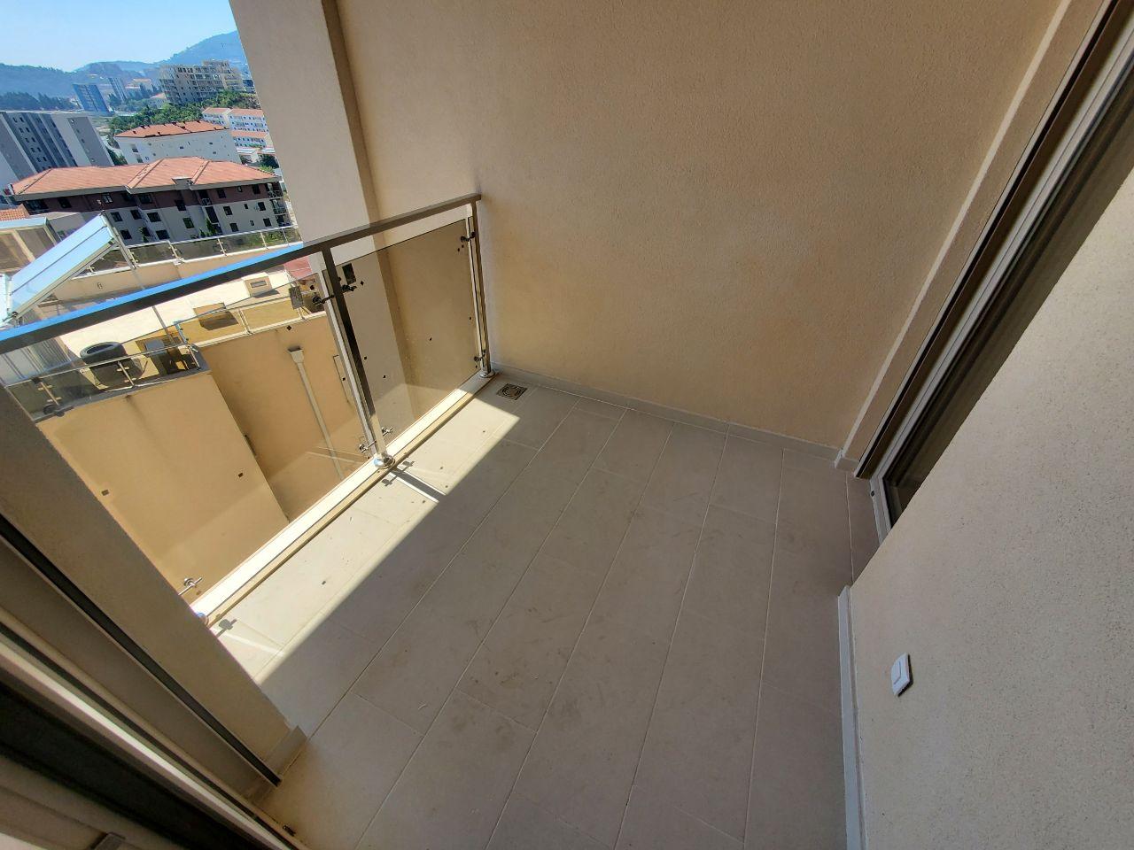 Balcony with panoramic glazing and city view in a residential building, Bečići, Montenegro. Light floor tiles.