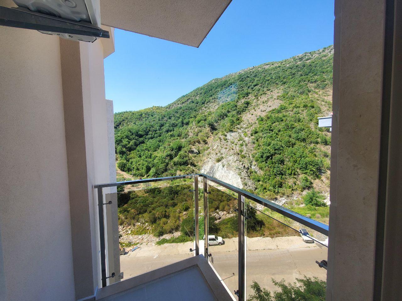 View from the balcony of green mountains in a residential building in Bečići, Montenegro: modern glass and metal railing.