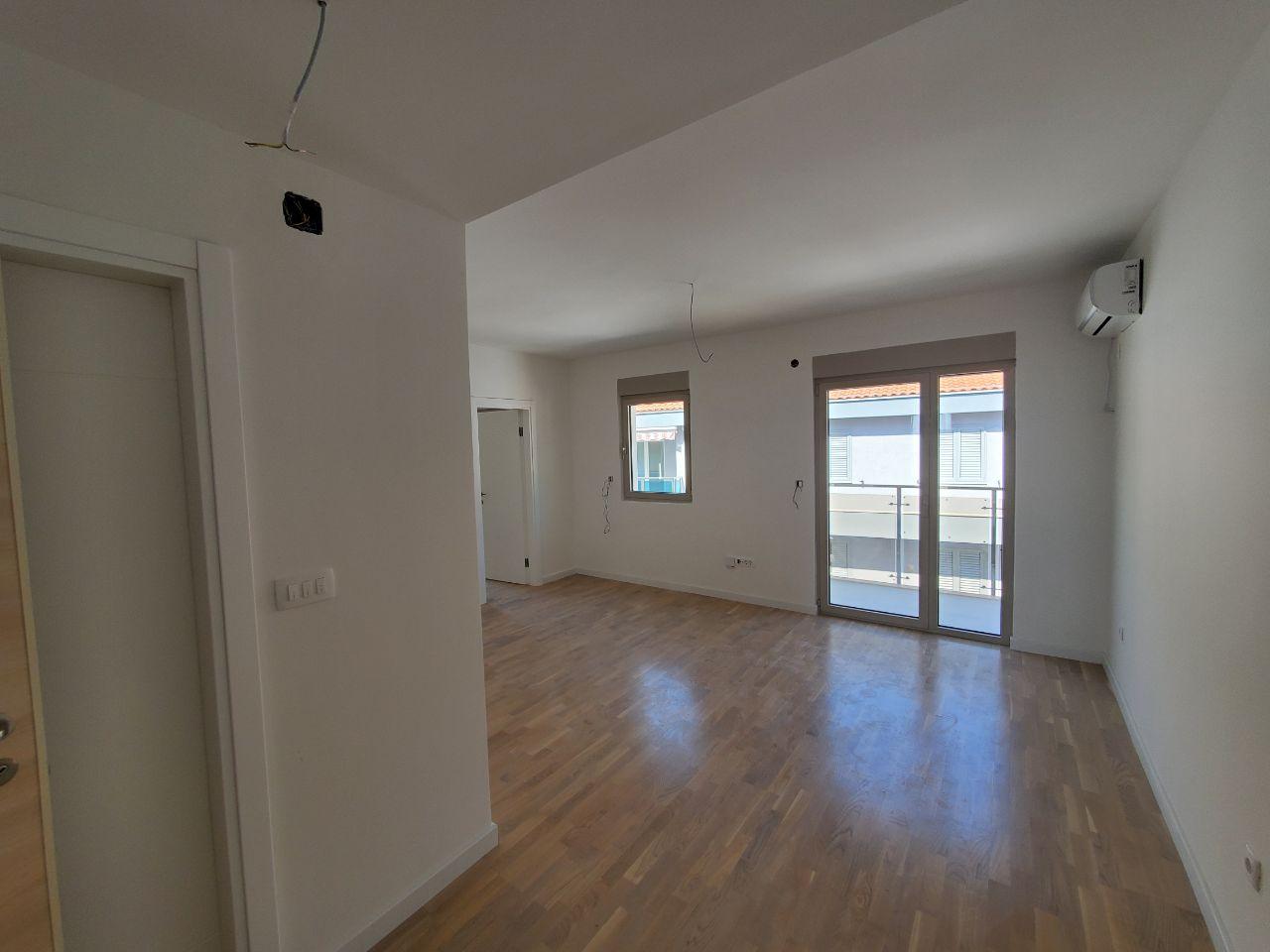 Bright living room with parquet flooring and access to the balcony in a new residential building in Bečići, Montenegro.