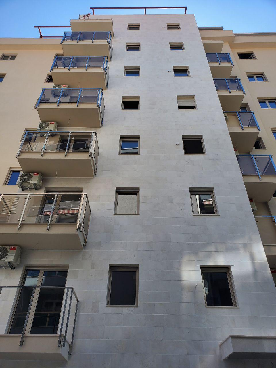 Facade of a modern residential building in Bečići, Montenegro: light-colored finish, balconies with glass railings, and air conditioners
