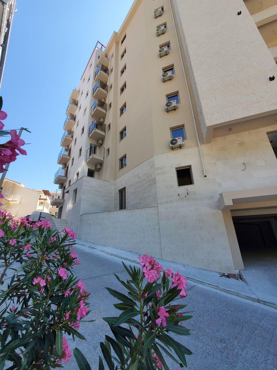 Modern apartment building in Bečići, Montenegro: building facade with balconies and blooming oleanders in the foreground.