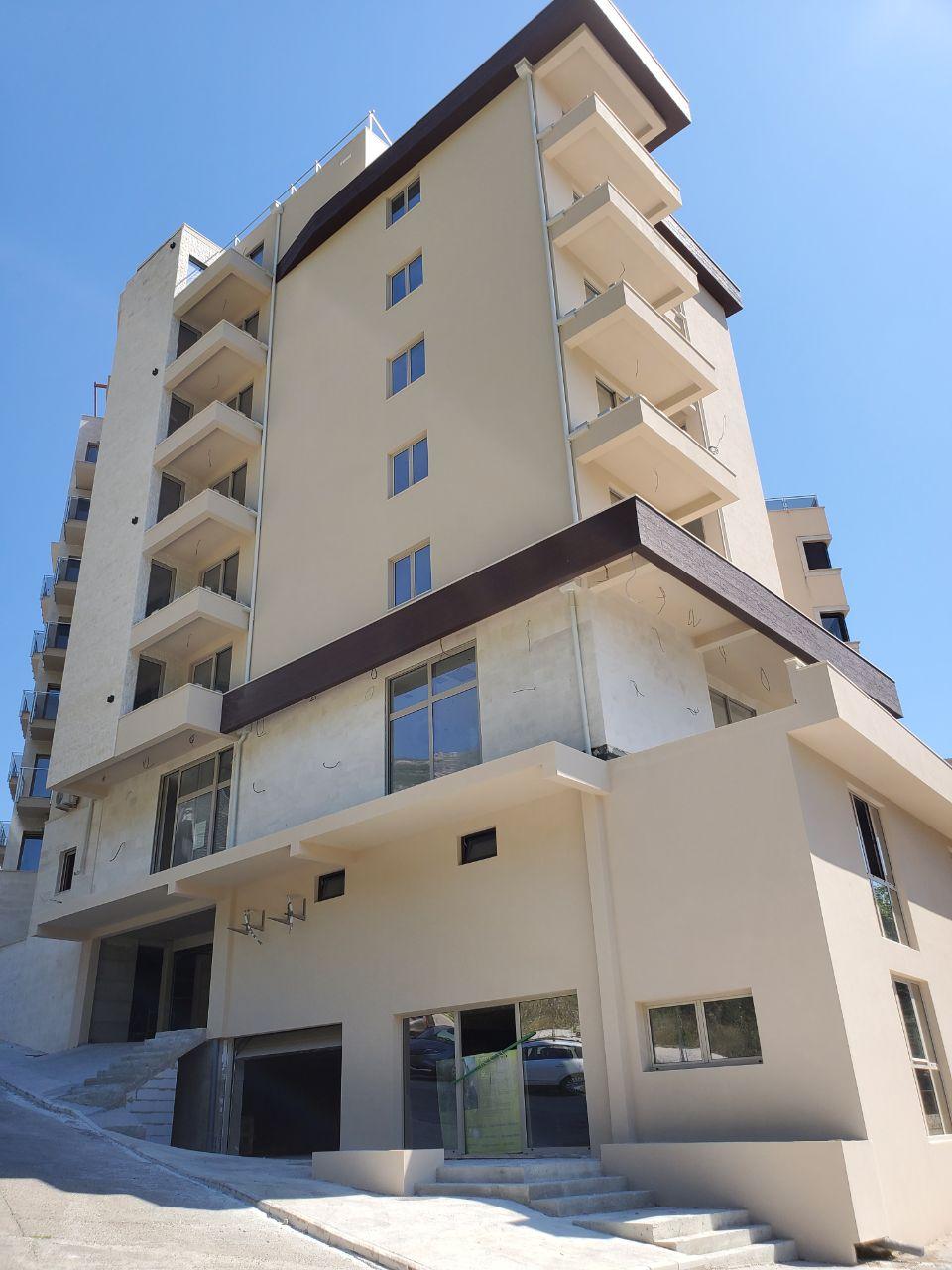 Modern multi-storey residential building in Bečići, Montenegro: building facade with balconies and panoramic windows.