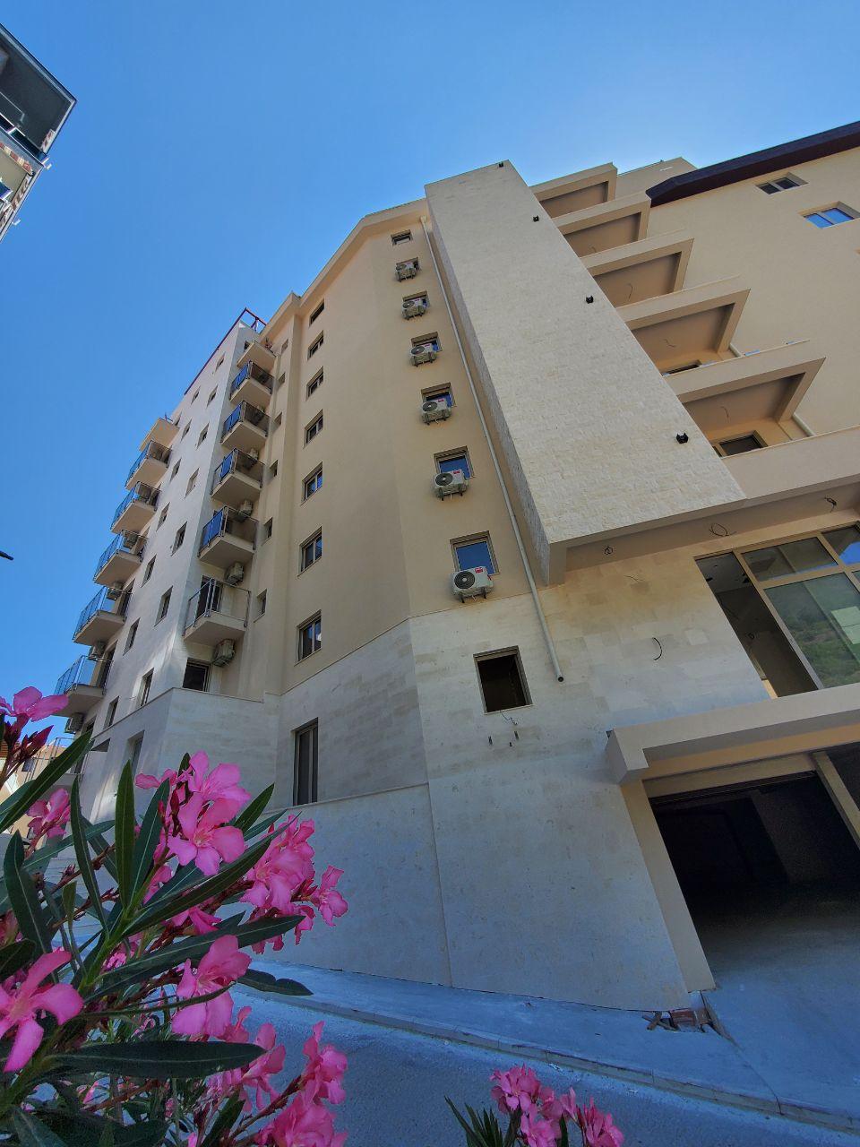 Modern residential building with balconies in Bečići, Montenegro: view of the building facade with blooming oleanders in the foreground.