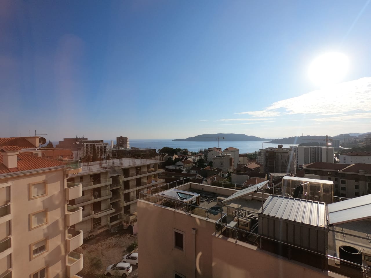 View from the balcony of the sea and the town of Bečići, Montenegro: a panorama of the coastline and residential development on a sunny day.