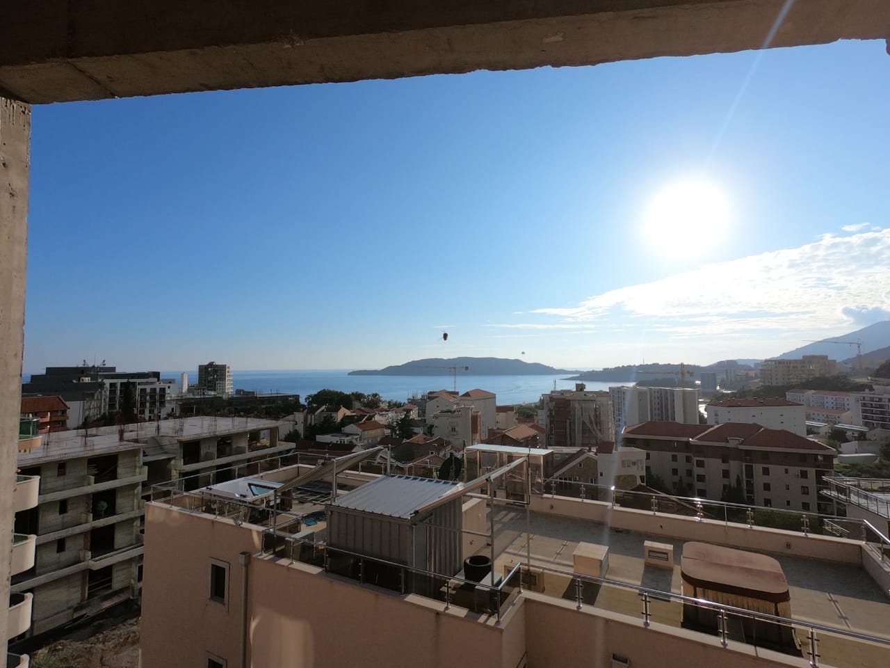 View from the balcony of the sea and the town of Bečići in Montenegro, a panoramic landscape with residential buildings and an island on the horizon.