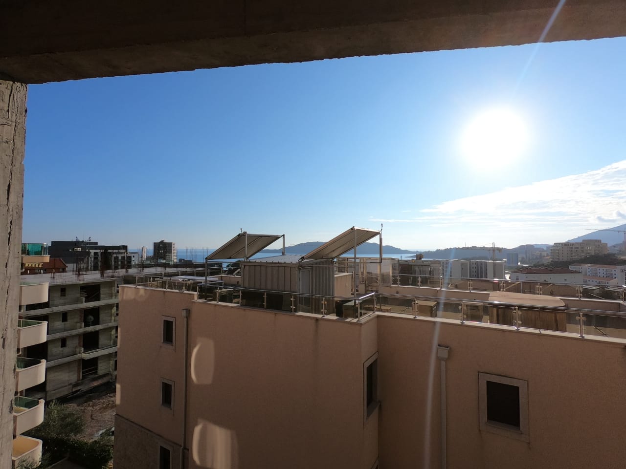 View from the balcony of a residential building in Bečići, Montenegro: city panorama, sunny weather, and the sea horizon.