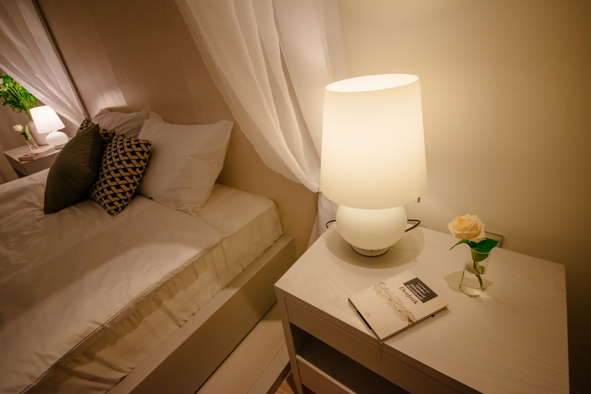 Cozy bedroom in an apartment, Kumbor, Montenegro: double bed, light-colored furniture, stylish lamps and decor.