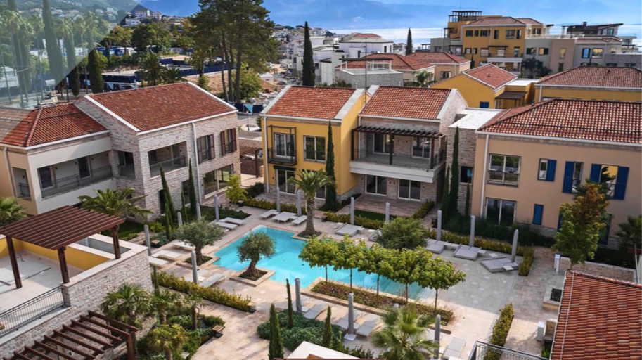 Aerial view of the Porto Novi residential complex in Kumbor, Montenegro: villas with tiled roofs and a shared swimming pool with a terrace.