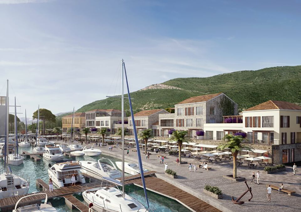 View of the luxury Porto Novi residential complex in Kumbor, Montenegro: the waterfront promenade with yachts, restaurants, and stone houses.
