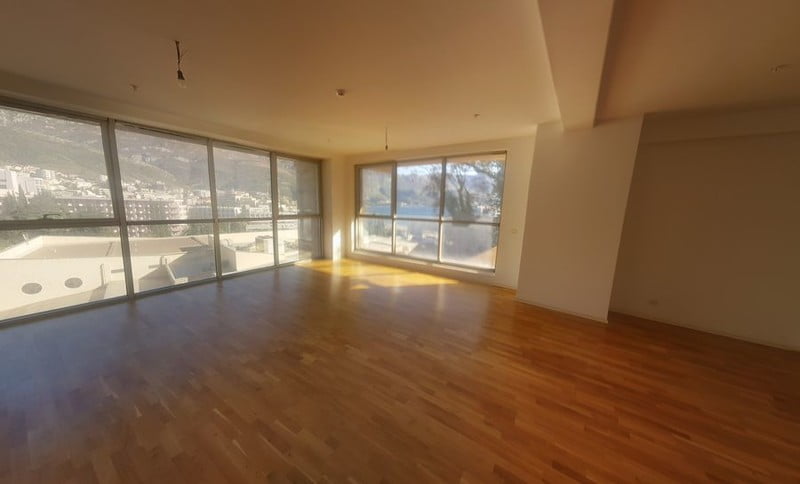 Spacious living room with panoramic windows and sea view in an apartment, Bečići, Montenegro. Bright interior, parquet flooring.