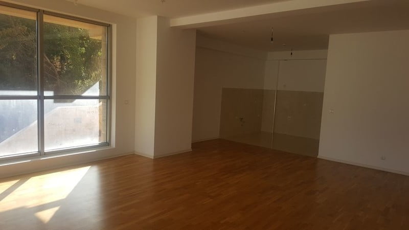 Bright living room with parquet flooring and panoramic windows in a new apartment in Bečići, Montenegro. Unfurnished.