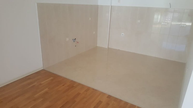 Kitchen area in an apartment in Bečići, Montenegro: light tiles on the floor and walls, prepared utility connections.