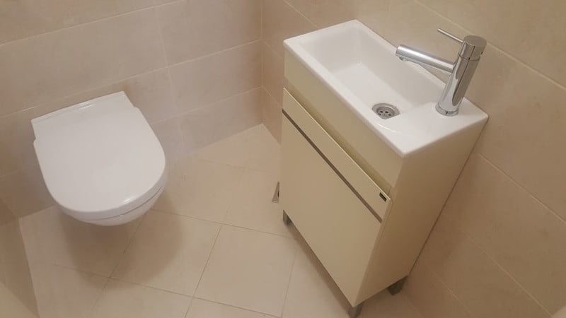 Modern bathroom with a wall-mounted toilet and compact sink in an apartment, Bečići, Montenegro.