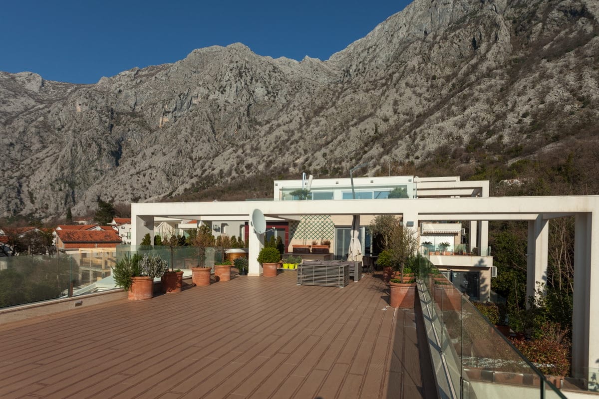 Spacious terrace with furniture and mountain views in an apartment, Ljuta, Montenegro. Modern finishes and glass railings.