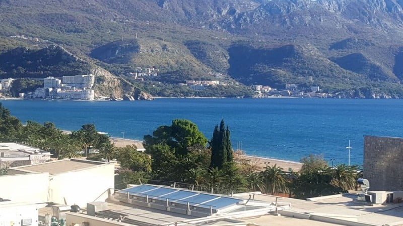 Panoramic view of the sea, beach, and mountains from an apartment in Bečići, Montenegro. View of the coastline and resort area.