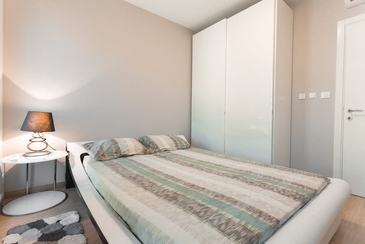 Cozy bedroom with a double bed and a white wardrobe in an apartment, the village of Ljuta, Montenegro. Modern interior.