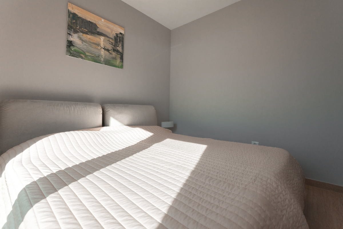 Cozy bedroom with a double bed in an apartment in Ljuta, Montenegro: modern interior and light tones.
