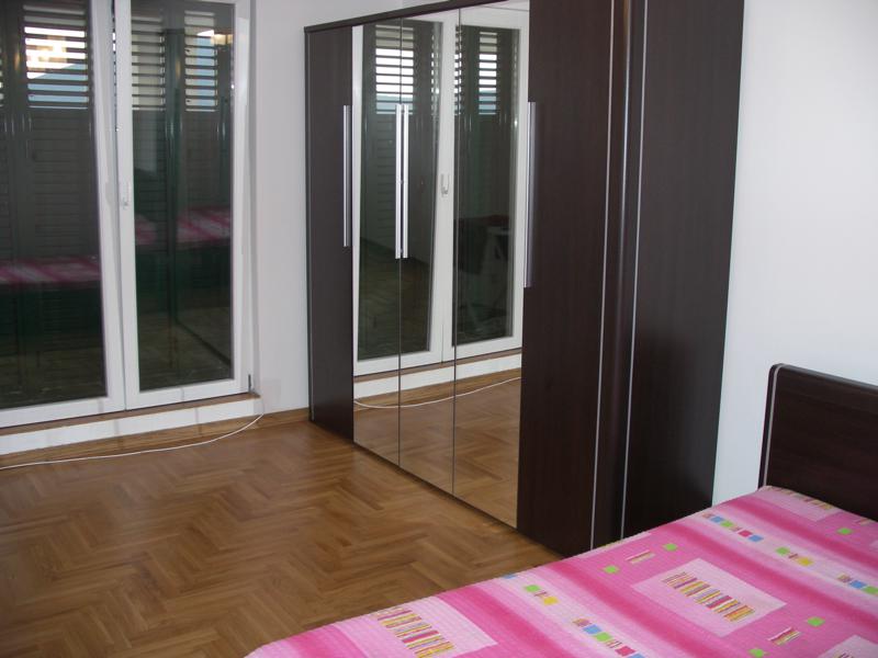 Bedroom in an apartment in Herceg Novi, Montenegro: parquet flooring, a large mirrored sliding wardrobe, and a bed with pink bedding.