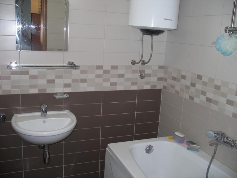 Modern bathroom with tiled walls in an apartment in Herceg Novi, Montenegro: bathtub, sink, and water heater installed.