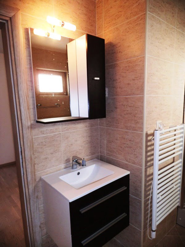 Modern bathroom in an apartment in Bečići, Montenegro: vanity with sink, illuminated mirror, and towel warmer.