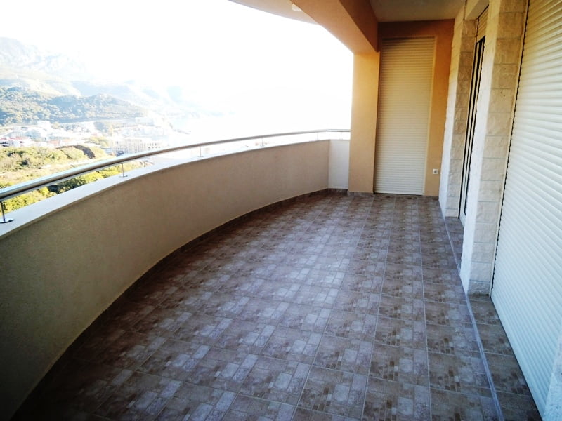 Spacious balcony with sea and mountain views in an apartment, Bečići, Montenegro: tiled floor and protective shutters.