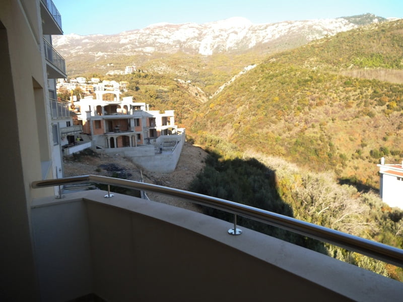 View from the apartment balcony in Bečići, Montenegro: a panorama of mountains, hilly landscape, and neighboring residential buildings under construction.