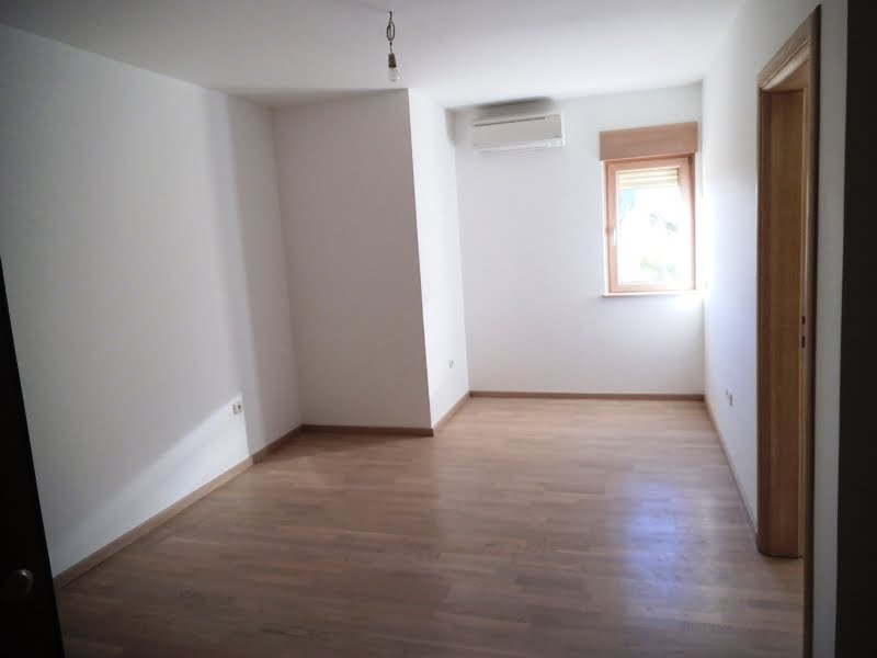 Bright bedroom with parquet flooring and air conditioning in an apartment, Bečići, Montenegro. Empty room with a window.