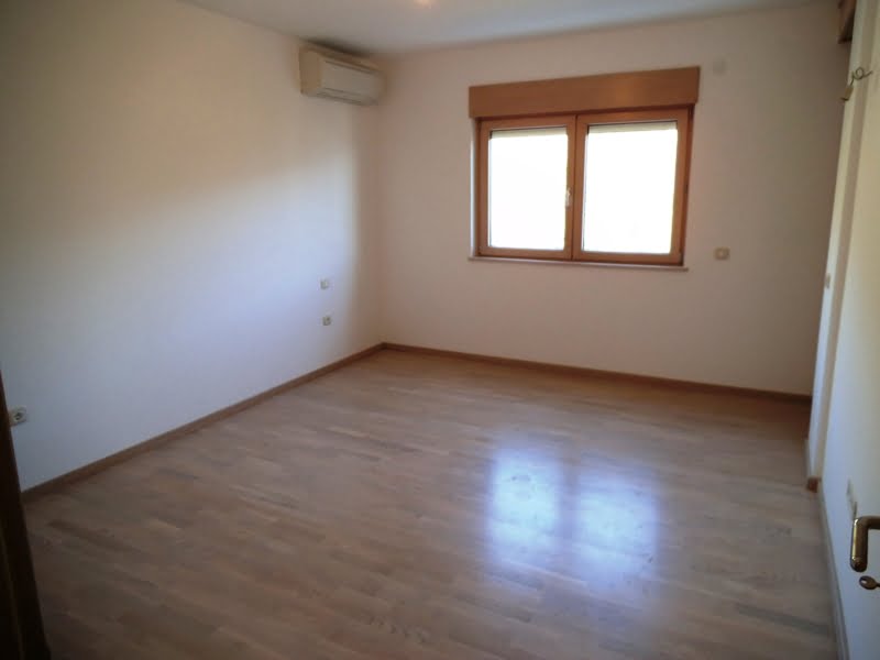 Bright empty bedroom with parquet flooring and air conditioning in an apartment in Bečići, Montenegro.